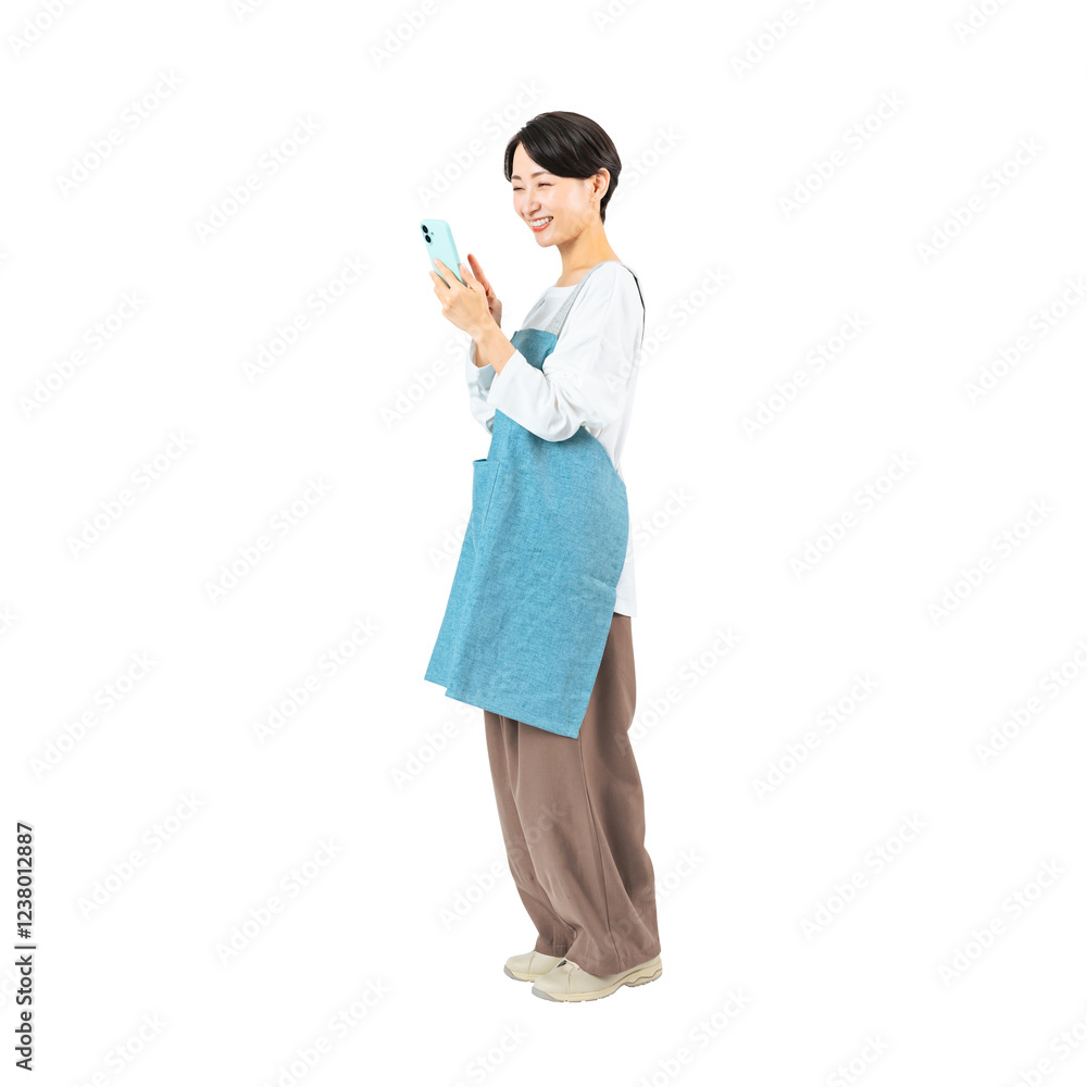 Poster 笑顔でスマホを使うエプロンをつけたミドル女性　手作業で精密に切り抜いた背景透過全身写真png