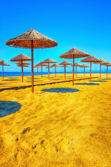 Row of wooden umbrellas at sandy beach, sea
