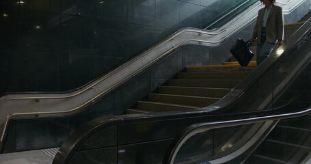 A woman in casual clothes goes down the stairs to the underpass
