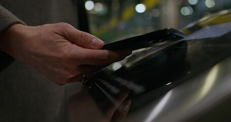 A woman puts her mobile phone to the terminal in the subway and passes through the turnstile. Close-up of her hand, an unrecognizable person