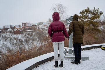 In a picturesque winter landscape, a man and a woman stand close together in the thick snow,...