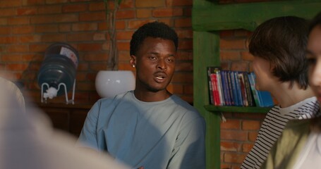 Bible Study Group. Young people talk in pairs. They are sitting at a round table in the room.