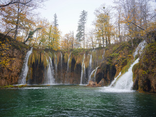 Fototapeta premium Plitvice Lakes in Croatia. Fabulous place with trees and stunning waterfalls in the forest at autumn. Great hiking destination with picturesque lakes and waterfalls, foggy season