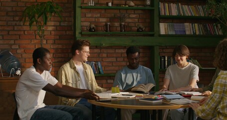 A group of young people of different nationalities join hands and begin prayer while sitting at a...