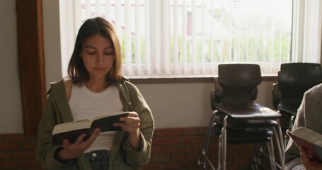 Young people of different nationalities are sitting in a circle. They are holding Bibles in their...