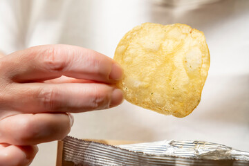Golden potato chips in human hand close-up.