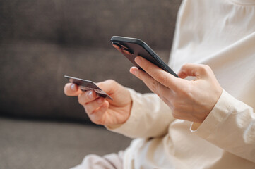 girl pays for purchases using smartphone holding bank card in hand