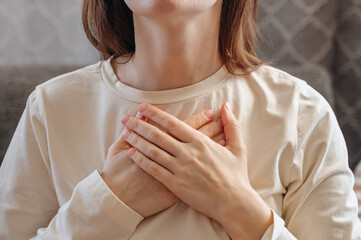 Close up of calm young woman holding hands on chest hearts feeling gratitude and appreciation....