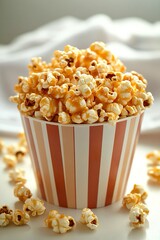 Vista frontale di un bicchiere di popcorn, su sfondo chiaro, popcorn sparsi sul bancone bianco.