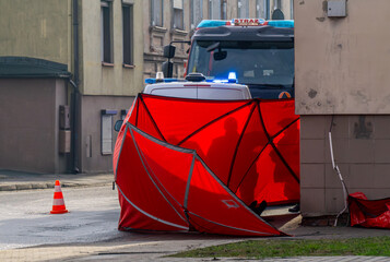 the scene of a fatal road accident in the city. bodies covered with a red fire brigade screen. A...