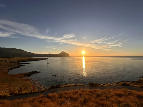 Serene sunset over coastal landscape with golden horizon and tranquil waters Macari Sicily