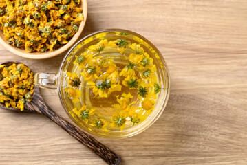 Chrysanthemum tea in cup glass with dried Chrysanthemum flowers, Healthy herbal drink, Table top view