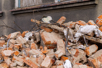 demolition of a residential building in the city center made of old red brick. lying brick on the ground. markings and signs of construction and road works.