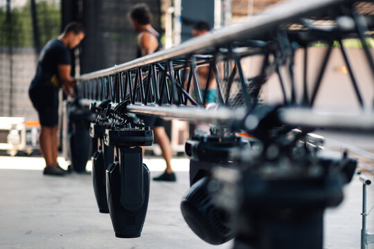 Stage lights being rigged by technicians on aluminum truss
