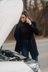 Businesswoman calling for help with broken car on roadside