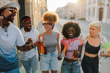 Cheerful friends toasting with bottles, enjoying a summer festival in the city