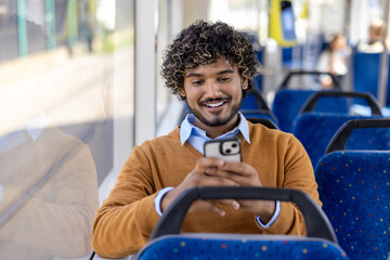 Public transport passenger uses phone while sitting. Man smiles contentedly typing message on...