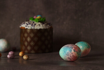 Easter colorful chicken eggs on dark background with Easter cupcake