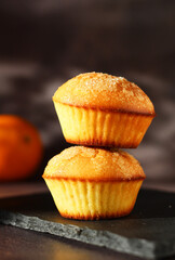 Dessert orange muffins in rows on dark background with orange