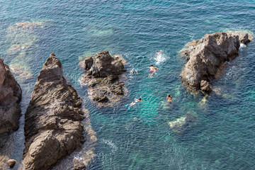 tourists snorkeling among the rocks of the sea