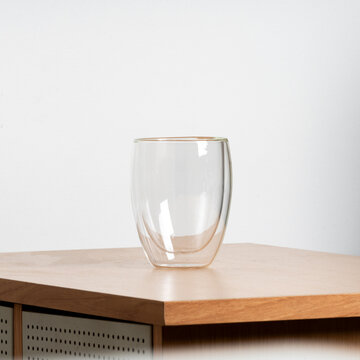 Empty glass of water on a wood table with clear reflections.