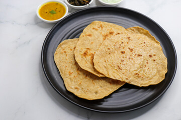 Roti and Sabzi. Indian vegetarian Thali includes bhindi fry, yellow daal tadka, cucumber raita, and chapati or tel paratha. Indian food is served in a plate or thali. Copy Space. healthy Veg Thali. 