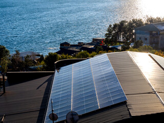 Solar panels on the small home rooftop near the beautiful lake view background. Photovoltaic solar...