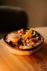 Salmon bowl with boiled red rice, avocado, poached egg, and homemade Caesar sauce on a wooden table