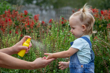 mother applies an aerosol insect spray to the child's body. Selective focus