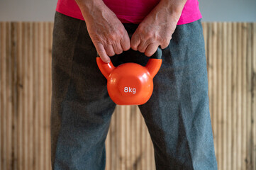 Hands holding an 8kg orange kettlebell