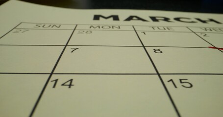 A schedule table with days of the week and numbers. One of the dates is crossed out with a red cross. Close-up