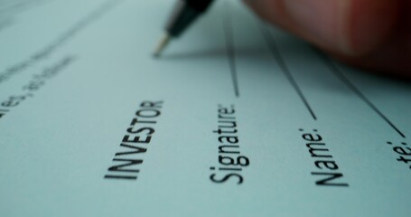 The man puts his signature on the document on behalf of the investor, close-up of his signature, an...