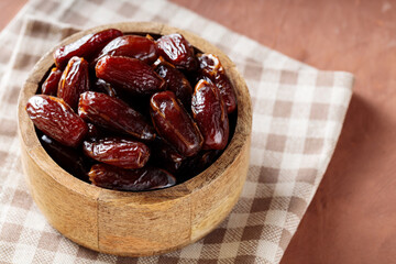 Dried Dates in Wooden Bowl on Beige Checkered Napkin