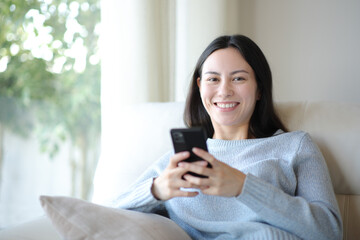 Happy asian woman looking at you holding phone