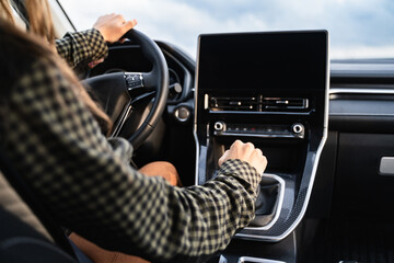An unrecognizable woman hand holding on the gearbox and changing speed in the car. Female driver...