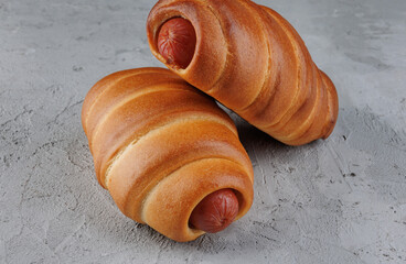 Two sausages in dough on concrete.