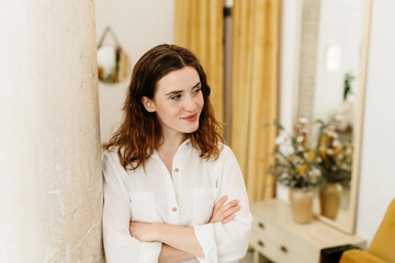 Thoughtful young woman leaning against a column indoors
