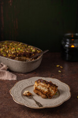 A piece of Dubai chocolate tiramisu with pistachio and chocolate ganache with candle. Italian tiramisu dessert with layers of lady finger biscuit and mascarpone. Professional food photography. 