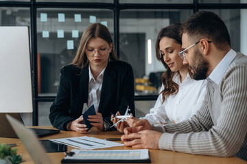 Looking at little toy plane. Business people are working in the office