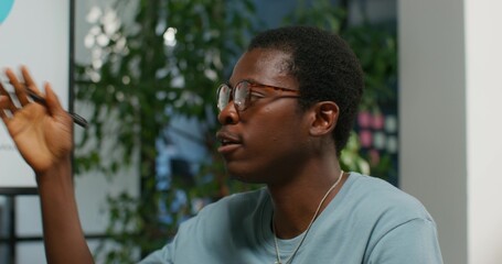 A man is talking while sitting at a table in an office meeting, close-up. Daylight