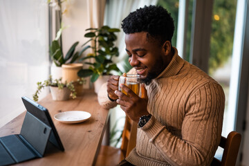 Young man using digital tablet to communicate online. He is sitting in bar,drinking tea and having video call.