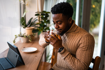 Young man using digital tablet to communicate online. He is sitting in bar,drinking tea and having video call.