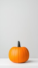 A large orange pumpkin with a black stem sits on a white shelf