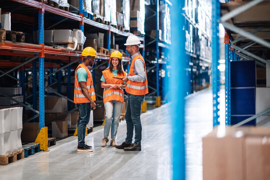 Warehouse workers and manager discussing logistics using digital tablet