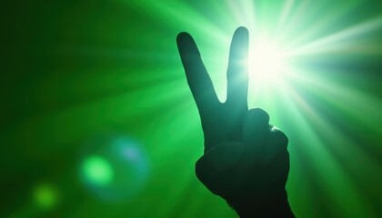 Silhouette of hand making peace sign with green light burst