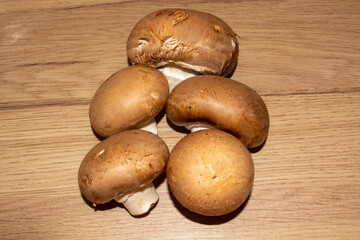 Five mushrooms of mushrooms on a wooden board. Food mushrooms brown champignons. Five brown champignons