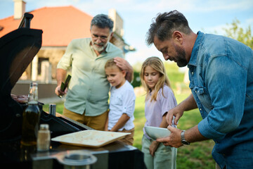 Fototapeta premium Happy family preparing food on a barbecue grill