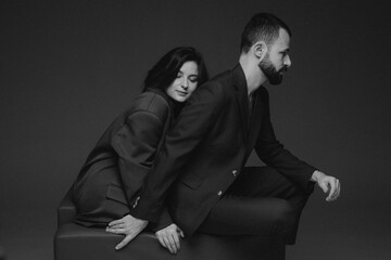 stylish couple of brunettes, bearded man and attractive woman dressed in classic brown suits on the naked body, studio photo shoot