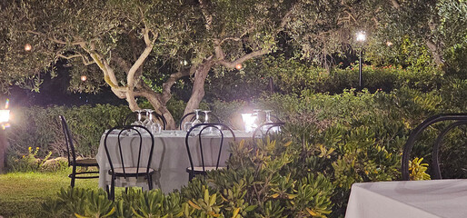 restaurant in the greenery of a garden with tables set in Agrigento for a dinner under the stars of a very hot summer