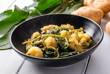 Piatto con cicorie e patate saltate in padella, un contorno saporito di ortaggi tipico della cucina del Sud Italia 